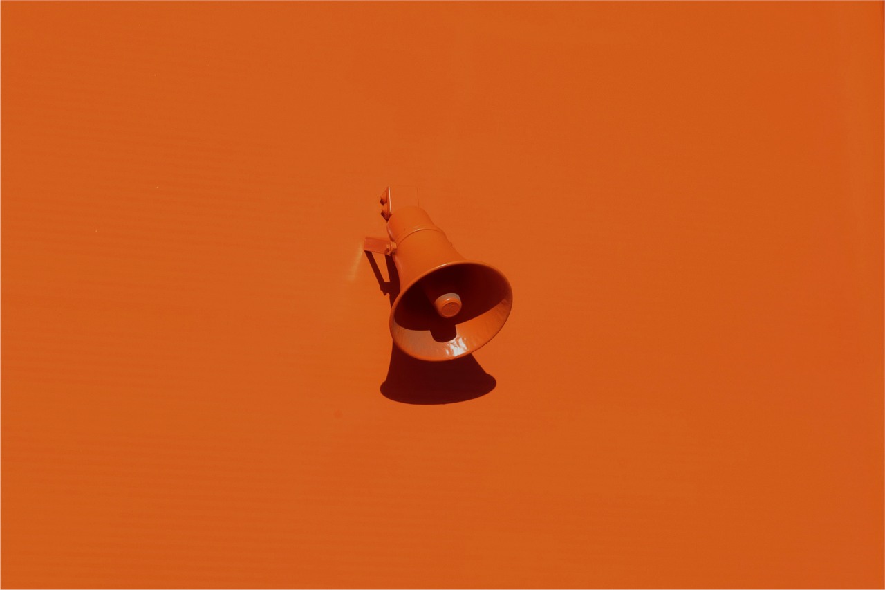 Pomarańczowy megafon zawieszony na pomarańczowej ścianie. 