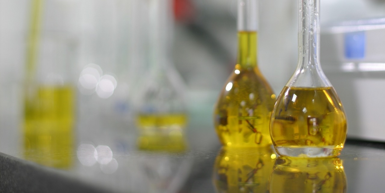 Parafiny i rozpuszczalniki – Grupa ORLEN. Kolby laboratoryjne z żółtym płynem umieszczone w laboratorium. 
